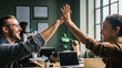 © Itsaraporn - Startup founders celebrating a small business success with a high-five in the office