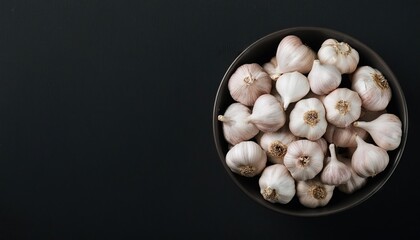 Wall Mural - garlic in a bowl on a black background, top view, copy space 