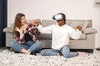 © prostooleh - Two young teenage girls sitting on a floor near bed wearing a virtual reality glasses