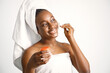 © prostooleh - Black girl in a bathrobe and towel on a head using jade roller