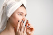 © prostooleh - Caucasian girl with towel on a head using jade roller isolated on white background