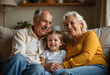 © chroniclez studio - grandmother, grandfather, and child bonding on a cozy couch. Warm lighting, soft textures, smiles, and laughter evoke love, care, and togetherness