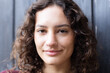 © Wavebreak Media - Smiling woman with curly hair looking at camera, close-up portrait
