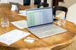 © Wavebreak Media - Laptop displaying spreadsheet on wooden table with documents and water glasses