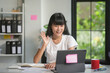 © amnaj - Young asian woman is waving while making a video call on a tablet in her home office