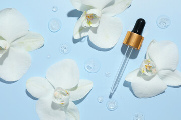 Poster - Beautiful orchid flowers and dropper with cosmetic product in water on light blue background, flat lay