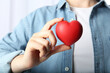 © New Africa - Woman holding red heart on light background, closeup