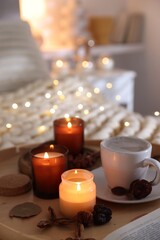 Wall Mural - Burning candles, lights, coffee and decor on bed indoors. Autumn atmosphere