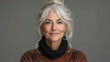 © sommersby - An older woman exudes confidence and warmth with her silver hair tied up and a soft sweater draped over her shoulders, creating an inviting atmosphere