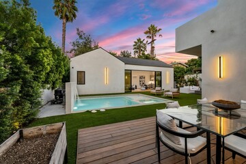 Modern backyard with pool and patio furniture at sunset.