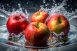© Butsarakham - A close up of four apples floating in a pool of water. The apples are red and green, and they are surrounded by water droplets. Concept of freshness and vitality
