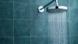 © sunchai - Water droplets falling from a modern showerhead, blue tiled bathroom background.