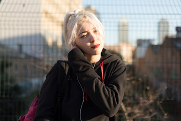 Young woman with headphones enjoying urban sunset