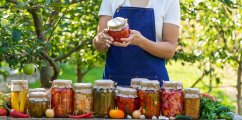 woman canning tomatoes cucumbers vegetables on the background of nature. Selective focus