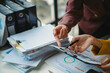 © amnaj - Business people having a conversation and analyzing financial documents while pointing at charts on a clipboard
