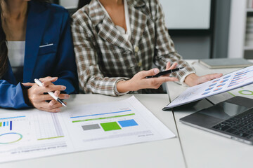 Wall Mural - Two businesswomen are discussing financial data, analyzing charts and graphs during a productive meeting