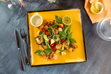 Wall Mural - Vibrant Seafood Assortment with Shrimp, Scallops, Fish, Greens, Avocado, and Cherry Tomatoes on a Yellow Plate