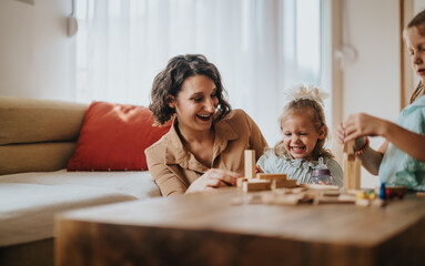 A joyful mother and her two daughters playing and laughing with wooden blocks at home. The image captures a warm and loving family moment filled with happiness.