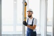© Serhii - handsome young man installing bay window in new house construction site