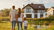 © Vitalii Shkurko - A family of three stands together outside, admiring their new home on a sunny day, symbolizing unity and new beginnings
