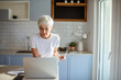 © Marko Geber - Senior woman managing finances on laptop at home