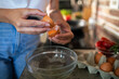 © Geber86 - Woman cracking an egg for healthy breakfast preparation in kitchen