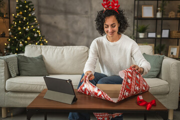 Mature woman wrap gift during video call, holiday spirit shines bright