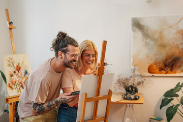 Wall Mural - Romantic happy artistic couple at creative art studio painting on easel