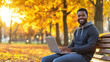 © Olga - Autumn Park Office: A joyful freelancer works from his laptop amidst vibrant fall colors. Perfect for promoting work-life balance, remote work programs, and lifestyle advertising.