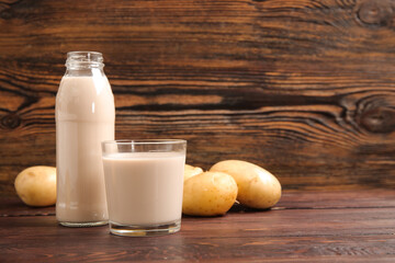 Bottle and glass of tasty potato milk on wooden background