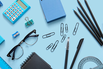 Wall Mural - Different school stationery, notebooks and glasses on blue background