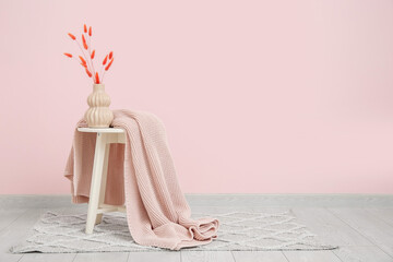 Wall Mural - Vase with dried flowers and blanket near pink wall