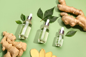 Wall Mural - Bottles of ginger cosmetic oil and leaves on green background