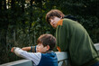 © Emvats - Two boys stand on a bridge, gazing into the distance. The scene captures a moment of quiet reflection as they share a peaceful moment outdoors surrounded by nature.