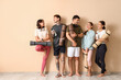 © Pixel-Shot - Group of sporty young people with yoga mats near beige wall