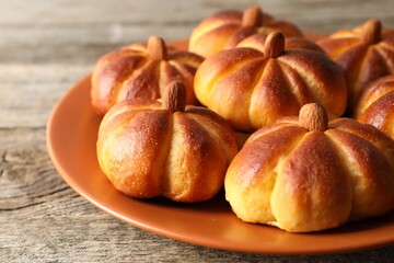 Tasty pumpkin shaped buns on wooden table, closeup