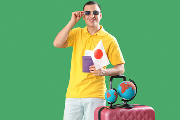 Wall Mural - Male tourist with Japanese flag and globes on green background