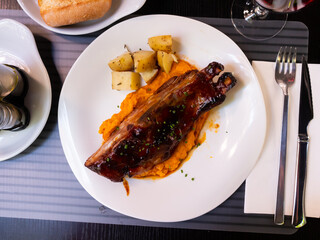 Wall Mural - Meaty grilled pork ribs in spicy barbecue sauce served with mashed batata and baked potatoes