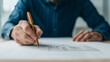 © ArtifyGraphy - A person sketches architectural plans on paper, showcasing creativity and design skills with a pencil in hand.