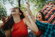 © qunica.com - Two young women laughing joyfully and enjoying a sunny day while relaxing on a colorful hammock in a park.
