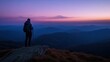 A hiker gazes at a serene mountain landscape during twilight.