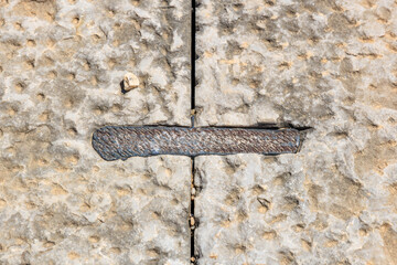 A metal bracket holds antique stone blocks together. Secrets of ancient architecture