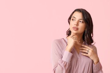 Poster - Fashionable young woman in beautiful rings and earrings on pink background