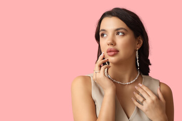 Poster - Fashionable young woman in beautiful jewelry on pink background