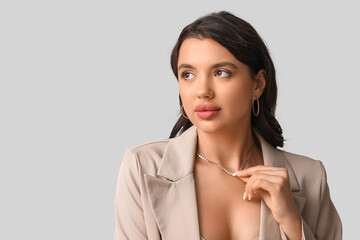 Poster - Fashionable young woman in beautiful necklace and earrings on grey background