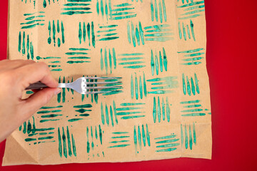 Wall Mural - Close up of decorative stamps with fork in paint and sheets of paper. Create unique wrapping paper, DIY crafting project for personalized designs. Christmas activity for kids,