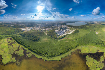 Big lake with green shores in bright sun light and city on horizon, aerial landscape. Recreation concept. Aerial view