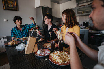 Poster - A group of friends gathers around a table enjoying a pasta meal. The scene depicts casual dining, conversation, and a cozy indoor atmosphere.