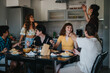 © qunica.com - A lively group of friends sharing a meal in a modern kitchen. The atmosphere is joyful, reflecting friendship and togetherness over a delicious dinner.