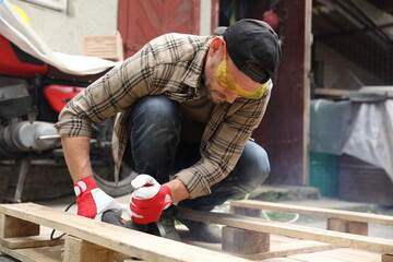 Poster - Man grinding wooden planks with angle grinder outdoors